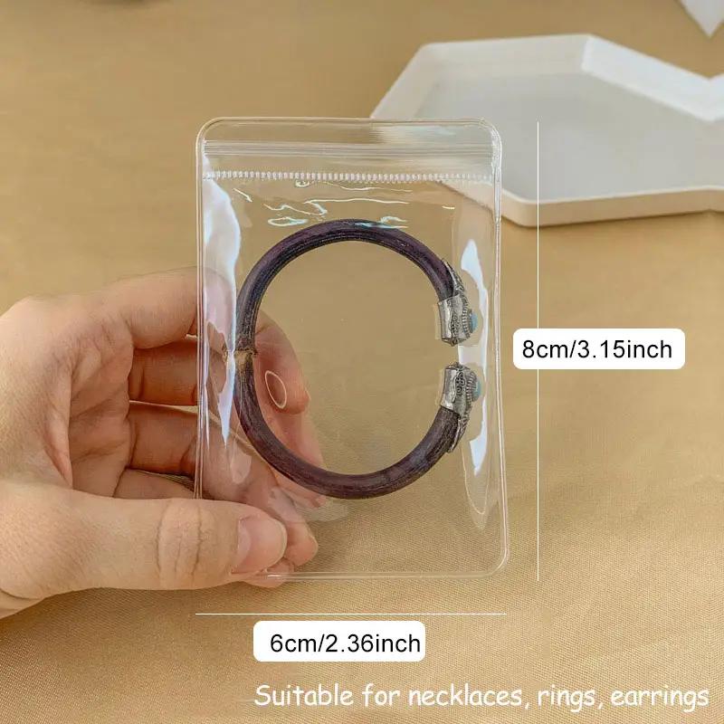 50/100 bolsas transparentes con cierre hermético de PVC, bolsas para joyería, resistentes al polvo y la oxidación, para guardar aretes, anillos, collares, pulseras, dijes y artículos pequeños, 2 tamaños a elegir (Cajas y organizadores de joyería)