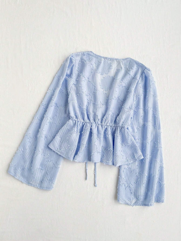 Camisa romantica de manga larga con cuello en V, dobladillo con volantes, mangas de campana y nudo al frente. Perfecta para vacaciones y ropa casual