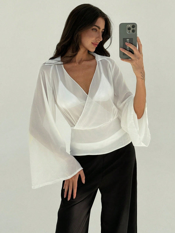 Blusa blanca de mujer con cuello en V profundo transparente, mangas largas abocinadas y munequeras con cintura suelta