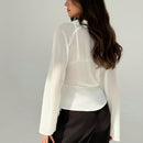 Blusa blanca de mujer con cuello en V profundo transparente, mangas largas abocinadas y munequeras con cintura suelta