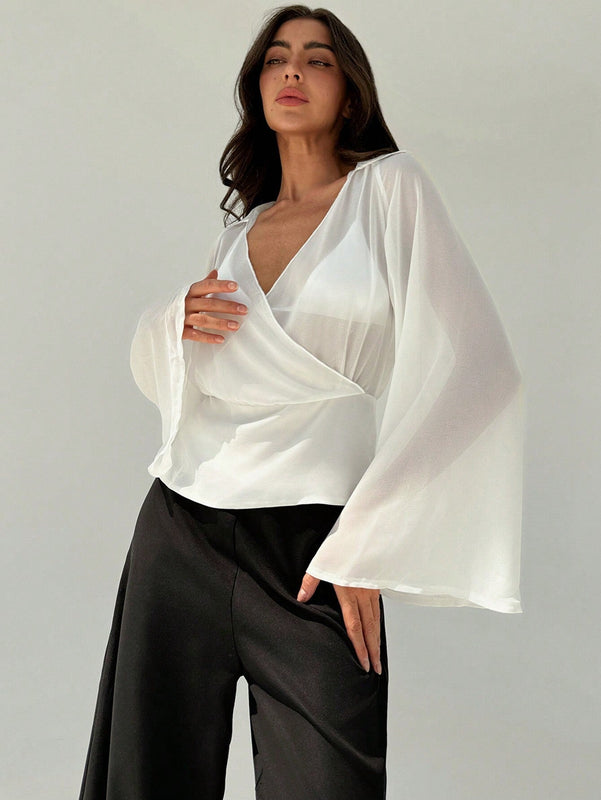 Blusa blanca de mujer con cuello en V profundo transparente, mangas largas abocinadas y munequeras con cintura suelta
