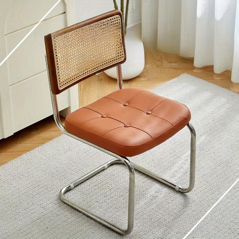 Una silla de comedor ergonómica hecha de ratán, con asas y asiento ajustable, perfecta para uso en patio y hogar. Se utiliza manualmente, tiene un respaldo robusto y es fácil de limpiar localmente, lo que la hace adecuada para adultos y ideal para suelos