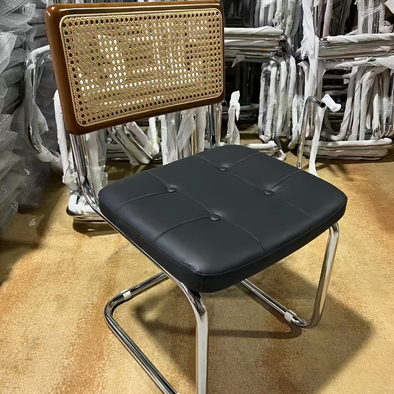 Una silla de comedor ergonómica hecha de ratán, con asas y asiento ajustable, perfecta para uso en patio y hogar. Se utiliza manualmente, tiene un respaldo robusto y es fácil de limpiar localmente, lo que la hace adecuada para adultos y ideal para suelos